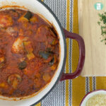 chicken and vegetables in a red sauce in a pot