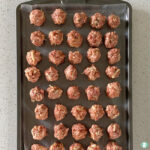 baking tray of raw meatballs