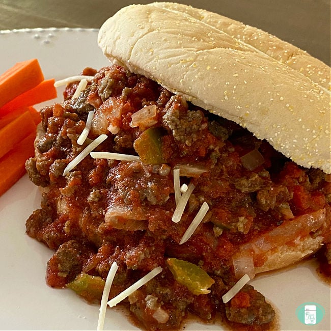 saucy ground meat mixture on a bun next to raw carrots