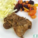 brown chicken on a plate with beet salad and cabbage