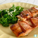 salmon fillets with sauce next to broccolini