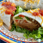 sliced burrito filled with refried beans, ground beef, and diced bell peppers topped with salsa and shredded cheese