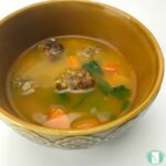 brothy soup with carrots, meatballs, and spinach floating in the broth