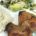 glazed chicken next to rice and a salad