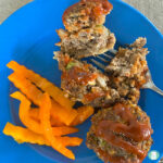 small meatloaves shaped in muffins next to sliced orange peppers on a plate