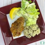 chicken on a plate with salad and wild rice