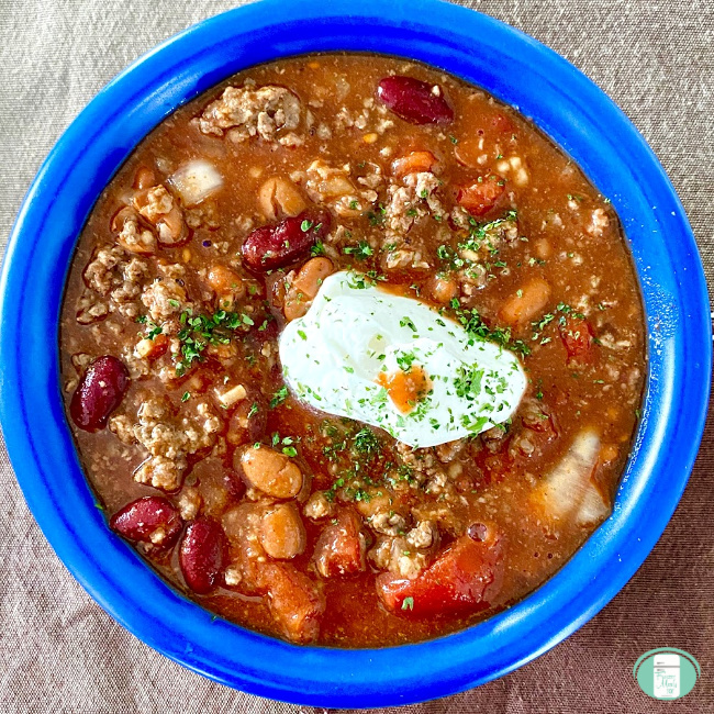 bowl of ground beef and beans topped with a dollop of sour cream