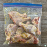 clear bag with raw chicken drumsticks and seasoning