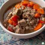 bowl with chunks of beef, carrots, and barley in a broth