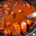 chicken pieces in a lot of red sauce in the slow cooker