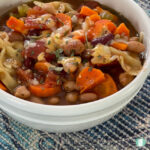 carrots, beans, and bowtie pasta soup in a white bowl