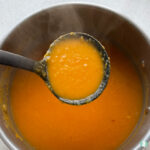 orange soup being ladled out of a pot