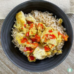 yellow chicken pieces and diced red peppers on rice