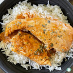 plate of rice topped with chicken in an orangey sauce