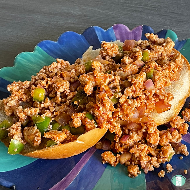 ground meat and diced green peppers on two bun halves on a plate