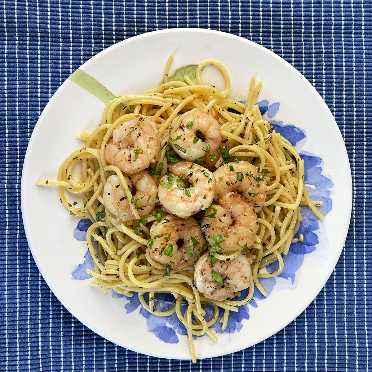 large garlic shrimp served over spaghetti sauce and garnished with fresh chopped herbs
