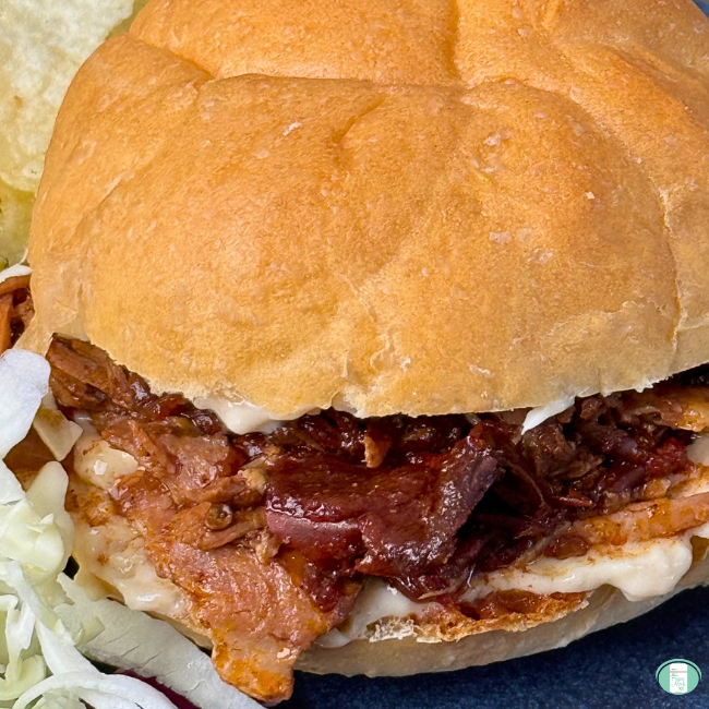 pulled pork in a rich sauce served on a kaiser roll with a bit of colesaw