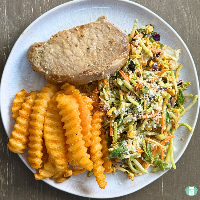 Steakhouse pork chop served with crinkle cut fries and coleslaw.