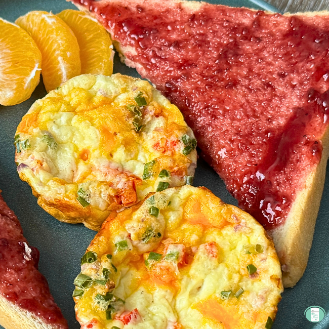 egg bites plated with toast with jam on it and orange segments